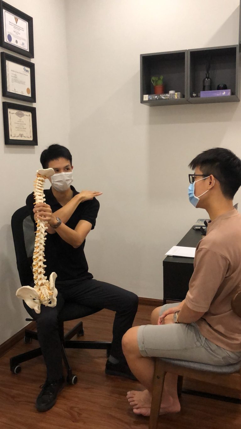 Certified chiropractor in KL explaining spinal alignment and treatment plan to a patient in a clinical setting.